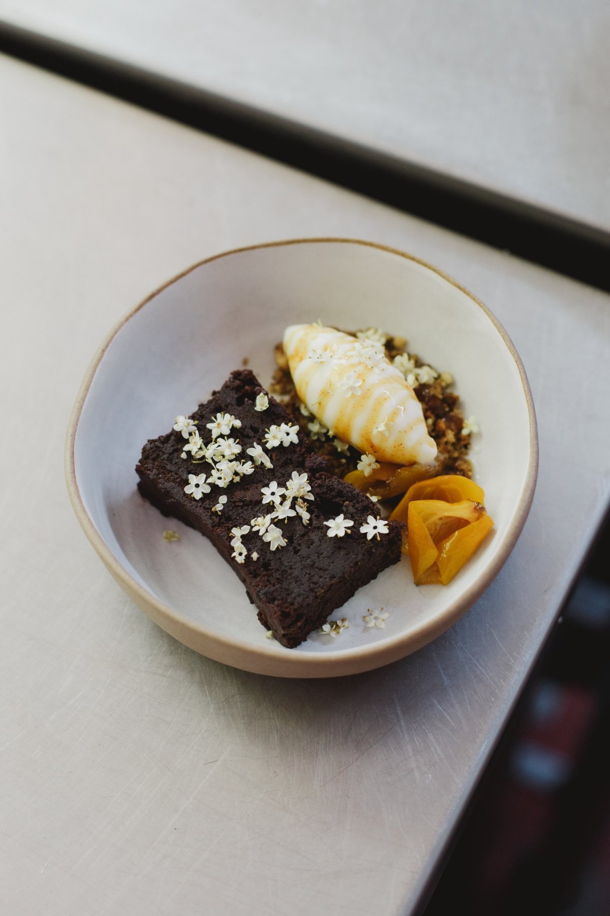 A dessert with fruit and delicate white flowers in a handmade bowl